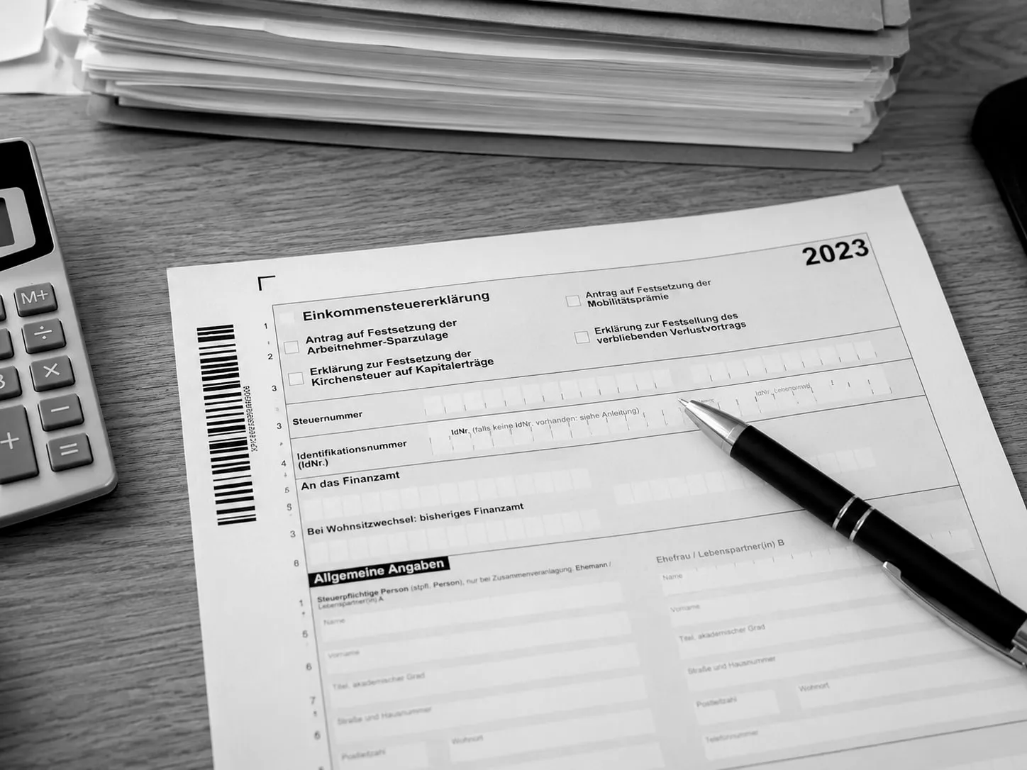 Einkommensteuererklärung 2023 mit Stift und Taschenrechner auf dem Schreibtisch